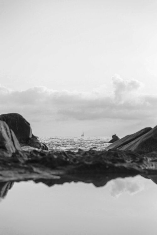 Blick aufs Meer mit einem Segelboot im Hintergrund